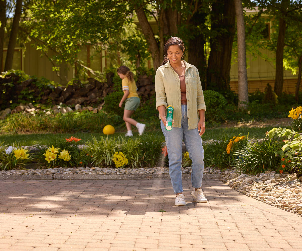 Woman using Spruce EZ-AIM spray on outdoor patio