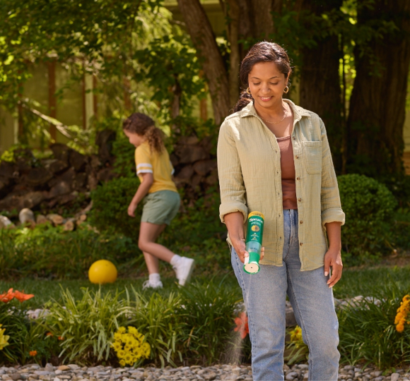 Woman applying Spruce EZ-AIM Spray to weeds on outdoor patio